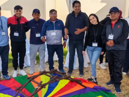 Equipo tomado de los brazos alrededor de un paracaídas de colores en el jardín.