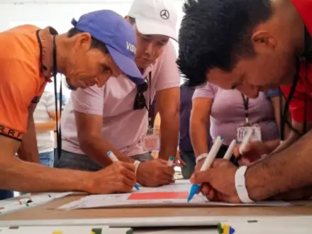 Participantes resolviendo un reto en equipo sobre la mesa, escribiendo juntos.
