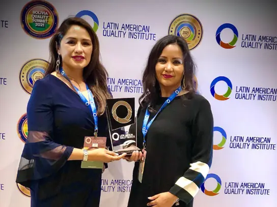 Dos representantes de Stolzel con el galardón ante el panel del Latin American Quality Institute.
